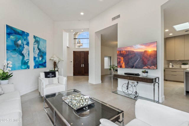 living room featuring a towering ceiling and a skylight