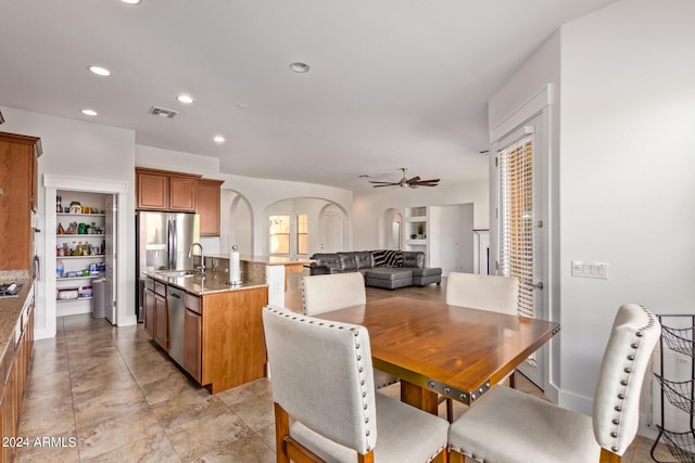 dining space with ceiling fan, built in shelves, sink, and light tile patterned floors