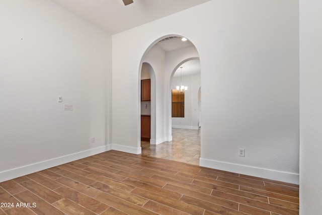 unfurnished room with hardwood / wood-style flooring and a notable chandelier