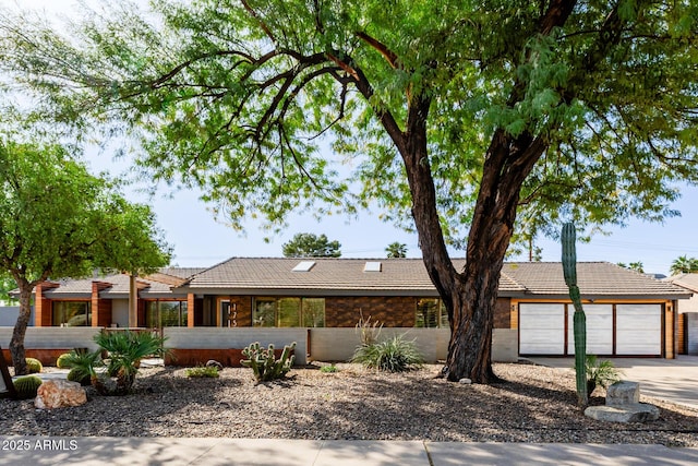 view of front facade featuring an attached garage, concrete driveway, and a tiled roof