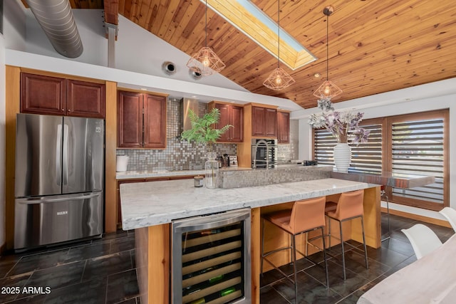 kitchen featuring a skylight, dark tile patterned flooring, wine cooler, freestanding refrigerator, and backsplash