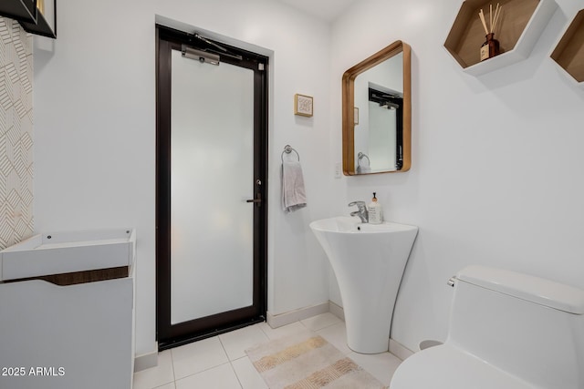 bathroom with toilet, baseboards, and tile patterned floors