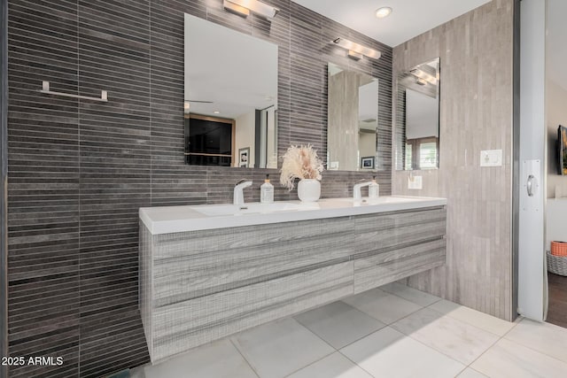 full bathroom featuring tile patterned flooring, a sink, tile walls, and double vanity