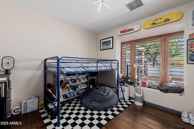 bedroom with wood finished floors, visible vents, and baseboards