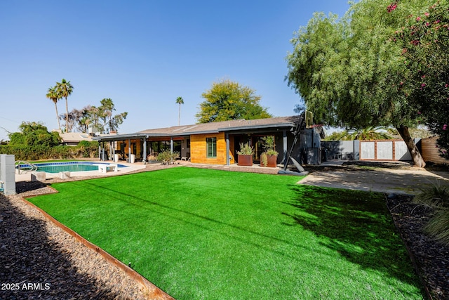 rear view of property featuring a lawn, a patio area, a fenced backyard, and a fenced in pool