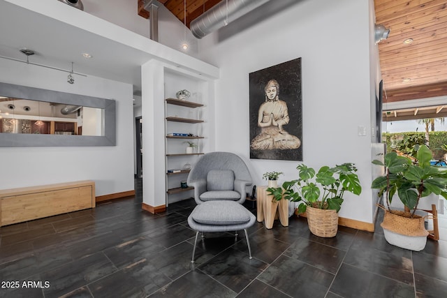 sitting room featuring wood ceiling, a towering ceiling, and baseboards