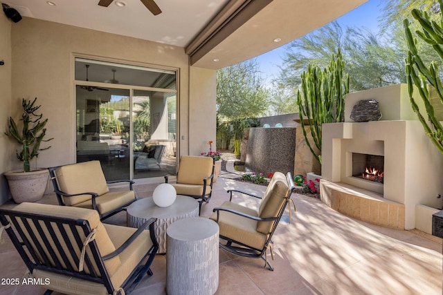 view of patio / terrace featuring a fenced backyard, a ceiling fan, and an outdoor living space with a fireplace