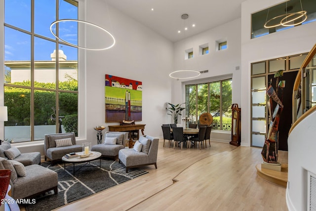 living room featuring visible vents, a high ceiling, baseboards, and wood finished floors