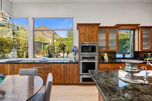 kitchen with brown cabinetry, stainless steel appliances, a wealth of natural light, and decorative backsplash