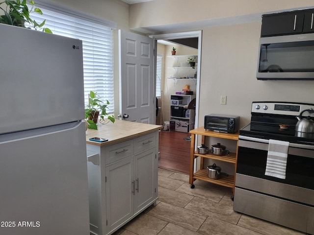 8221 E Garfield St Unit L109, Scottsdale, AZ 85257 - kitchen with stainless steel appliances, light countertops, white cabinets, and light tile patterned floors