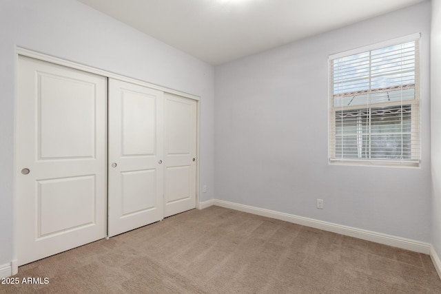 unfurnished bedroom featuring light carpet and a closet