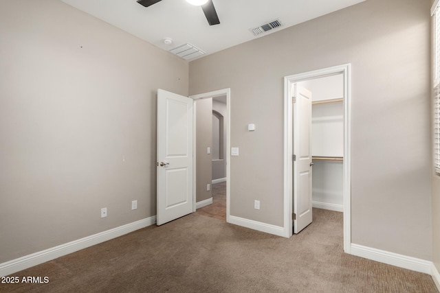 unfurnished bedroom featuring ceiling fan, light colored carpet, a closet, and a walk in closet