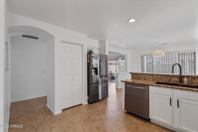 4323 E Dublin St, Gilbert, AZ 85295 - kitchen with stainless steel appliances, arched walkways, a sink, white cabinetry, and dark stone counters