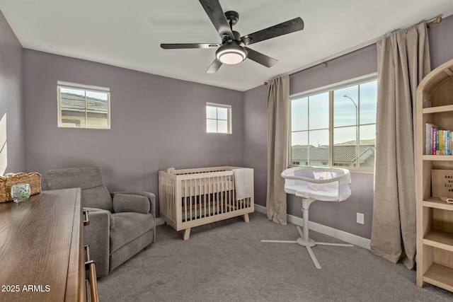 carpeted bedroom with ceiling fan and a nursery area