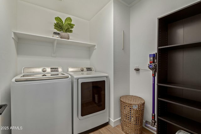 clothes washing area featuring light wood-type flooring and washing machine and clothes dryer