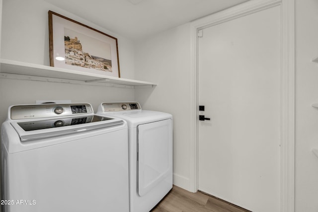 clothes washing area with light wood-style flooring and separate washer and dryer