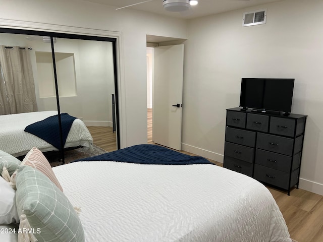 bedroom featuring a closet, light wood-style flooring, baseboards, and ceiling fan