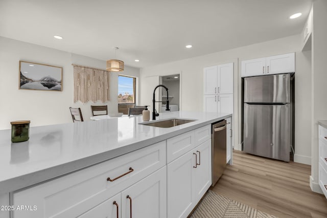 kitchen with stainless steel appliances, a sink, white cabinets, recessed lighting, and light wood-type flooring