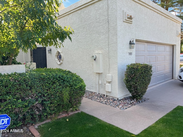 view of side of home with stucco siding and an attached garage
