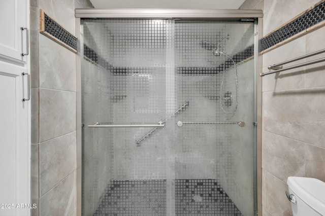 full bathroom featuring toilet, a stall shower, and tile walls