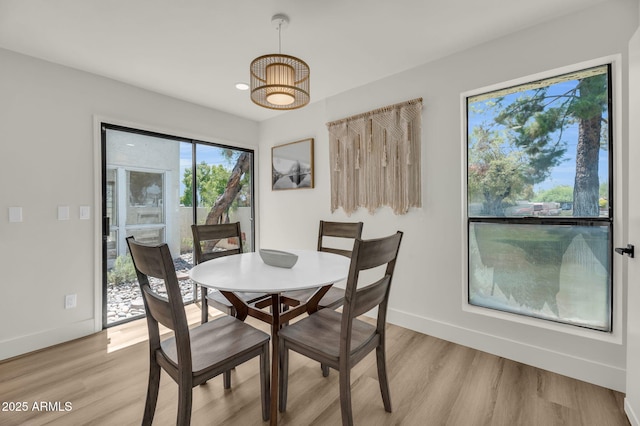 dining space with baseboards, light wood finished floors, and a chandelier