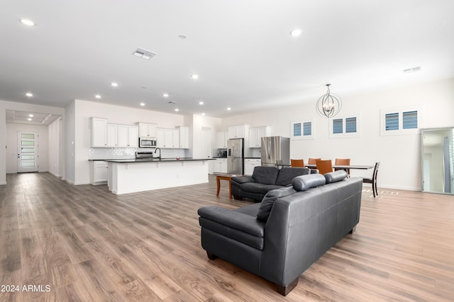 living room featuring an inviting chandelier, light hardwood / wood-style flooring, and sink