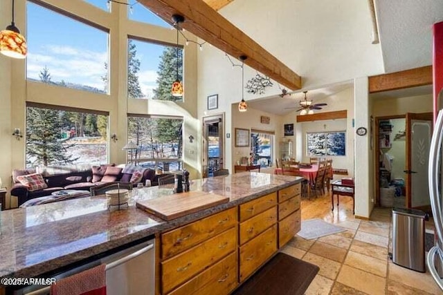 kitchen featuring pendant lighting, high vaulted ceiling, ceiling fan, dark stone countertops, and beamed ceiling