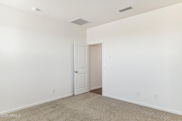 empty room with baseboards, visible vents, and carpet flooring