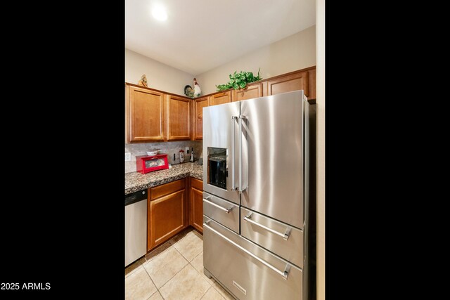 4245 E Ficus Way, Gilbert, AZ 85298 - kitchen with appliances with stainless steel finishes, brown cabinetry, light tile patterned flooring, backsplash, and light stone countertops