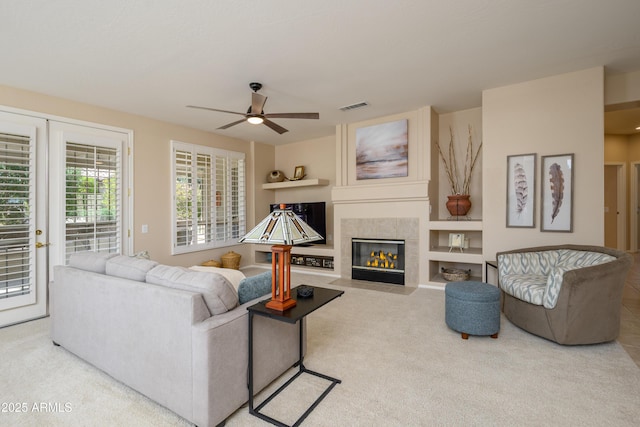15134 W Waterford Dr, Surprise, AZ 85374 - carpeted living room with visible vents, ceiling fan, and a tile fireplace