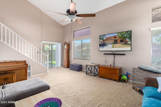 carpeted living room with ceiling fan and high vaulted ceiling