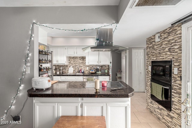 kitchen with decorative backsplash, a peninsula, white cabinetry, black appliances, and light tile patterned floors