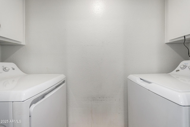washroom with cabinet space, washing machine and dryer, and a textured wall
