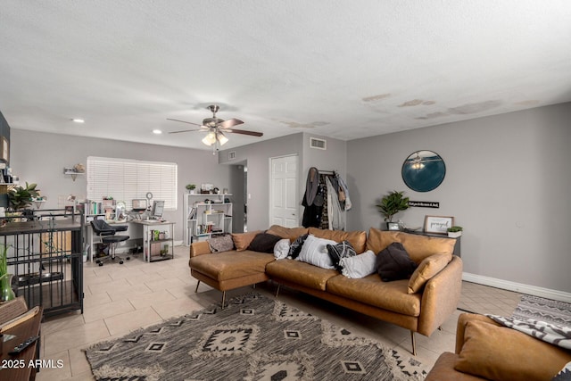 living area with a textured ceiling, light tile patterned floors, baseboards, visible vents, and ceiling fan