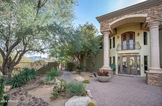 view of patio with a mountain view, french doors, and a balcony