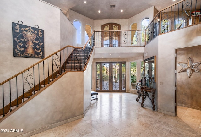 foyer entrance featuring a towering ceiling and french doors