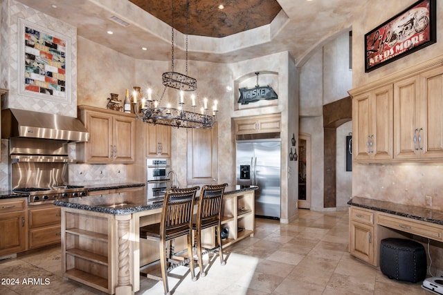 kitchen with hanging light fixtures, a high ceiling, an island with sink, a breakfast bar, and appliances with stainless steel finishes