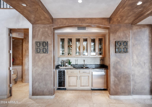 bar featuring stainless steel appliances, wine cooler, dark stone counters, and sink