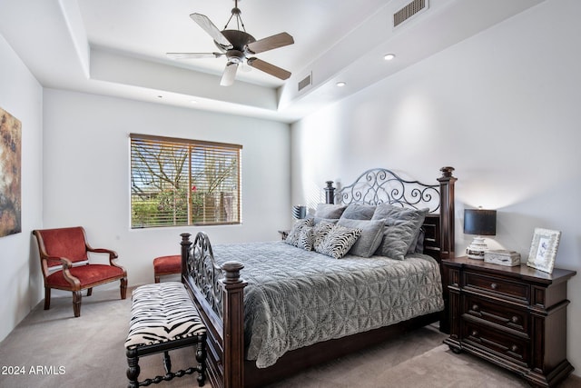 bedroom with a tray ceiling, ceiling fan, and light carpet