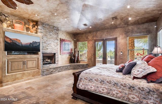 bedroom with ceiling fan, a stone fireplace, access to outside, and french doors