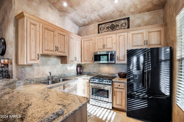 kitchen with light stone countertops, sink, light brown cabinets, and appliances with stainless steel finishes