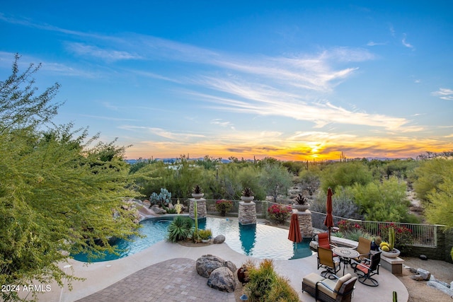 pool at dusk with a patio area