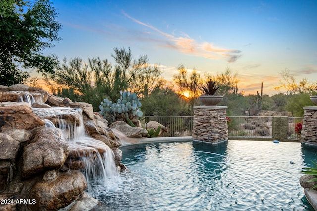 pool at dusk featuring pool water feature