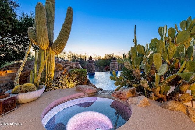 pool at dusk with an in ground hot tub