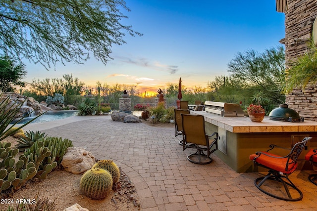 patio terrace at dusk with area for grilling and exterior kitchen