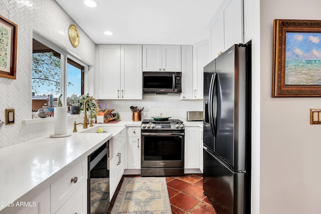 kitchen featuring sink, tasteful backsplash, appliances with stainless steel finishes, dark tile patterned flooring, and white cabinets