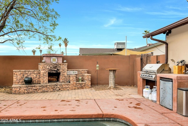 view of patio / terrace featuring area for grilling, central air condition unit, and an outdoor kitchen