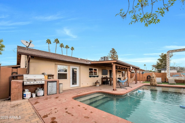 back of property with a fenced in pool, a patio, and area for grilling