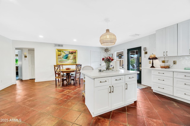 kitchen with white cabinetry, hanging light fixtures, decorative backsplash, and a kitchen island