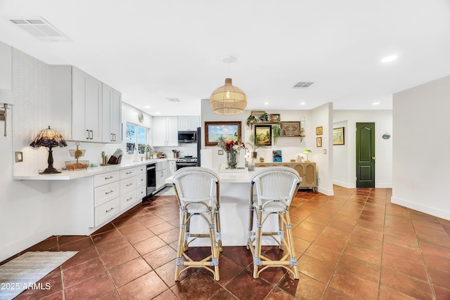 kitchen with a breakfast bar area, white cabinetry, hanging light fixtures, appliances with stainless steel finishes, and dark tile patterned flooring